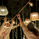 People holding light bulbs with string lights and lanterns in the background