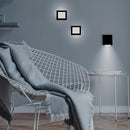 Modern interior with a wire chair, blanket, and wall-mounted lights.