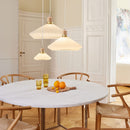 Dining room with a round marble table, wooden chairs, and pendant lights.