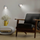 Modern interior with a black leather armchair, white table, and wall lights.
