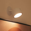 White wall-mounted light fixture on a neutral wall with a colorful abstract painting below.