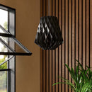 Pilke Wooden Pendant Light in Black Birch Wood against a wooden panelled wall with a black window frame.