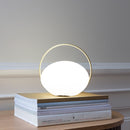 Umage Orbit Portable Table Lamp on some books on a table casting a soft glow. The portable light is great for reading