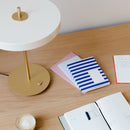 White Umage Asteria Table Lamp view from above as it sits on a desk with notepads