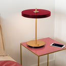 Red Umage Asteria Table Lamp on a Brass and pink bedside table .