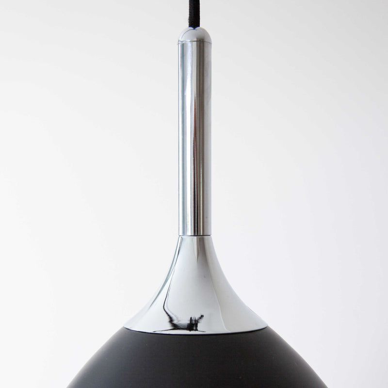 Black pendant light with a white accent on a plain background