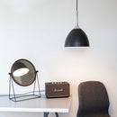 Modern interior with a Halo Design black pendant light, round mirror, and Marshall speaker on a white surface.