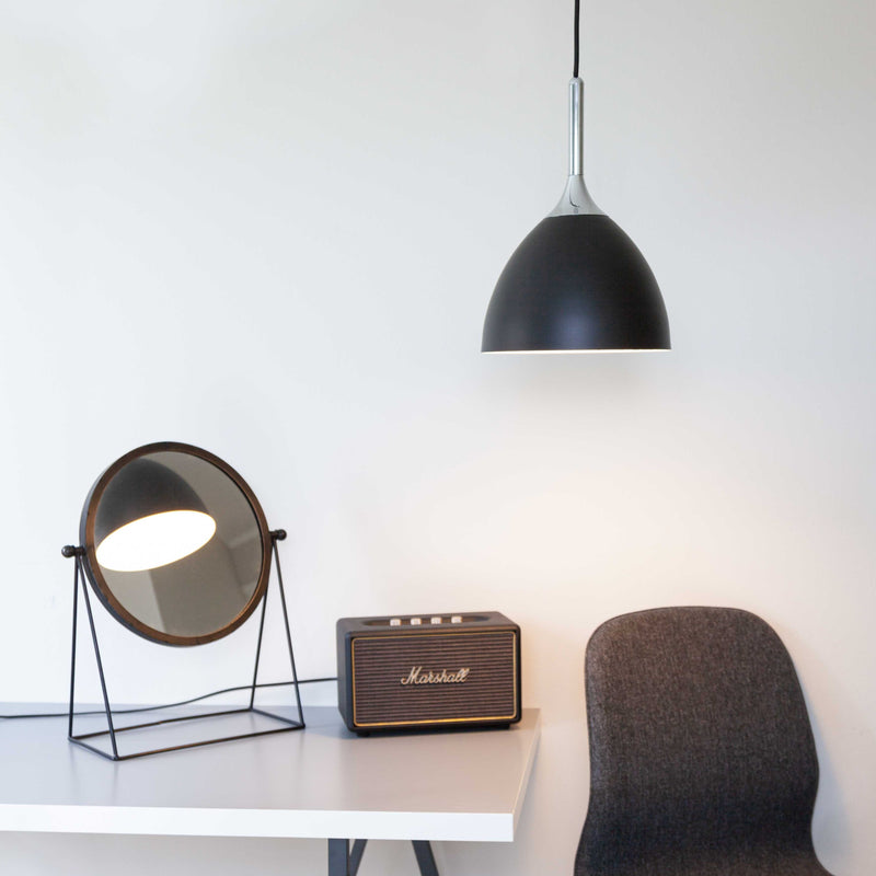 Modern interior with a black pendant light, round mirror, and Marshall speaker on a white surface.