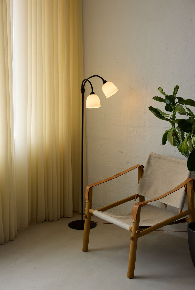 Modern room interior with a floor lamp, chair, and plant.