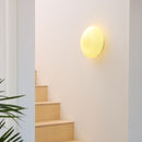 Staircase with a wall-mounted Halo Design Candy Wall light fixture on a white wall.
