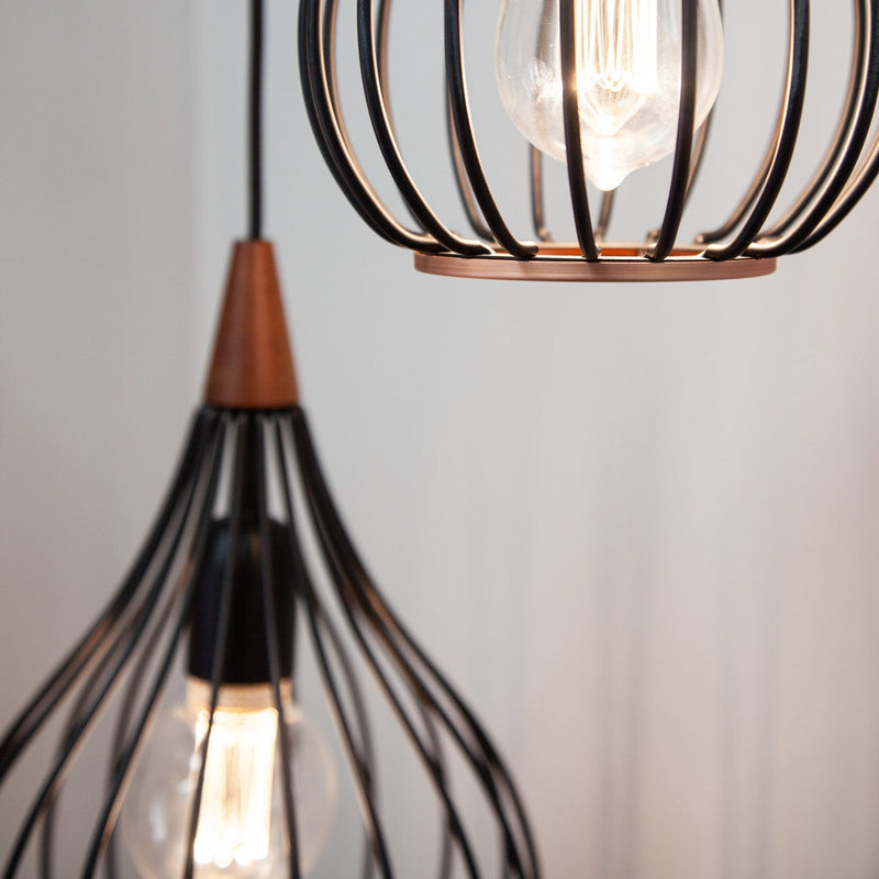 Close-up of a modern pendant light with black wire cage design on a neutral background