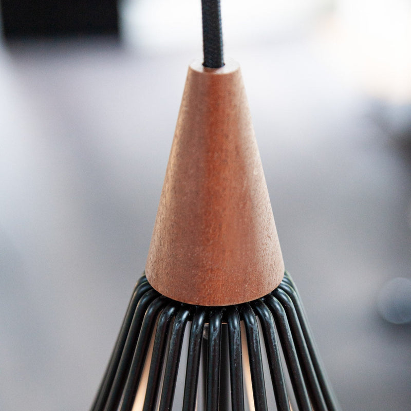 Close-up of a pendant light with wooden top and metal base on a blurred background