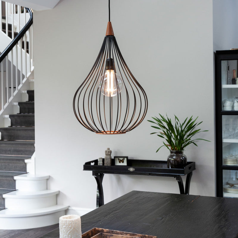 Modern pendant light hanging in a room with a staircase and table.