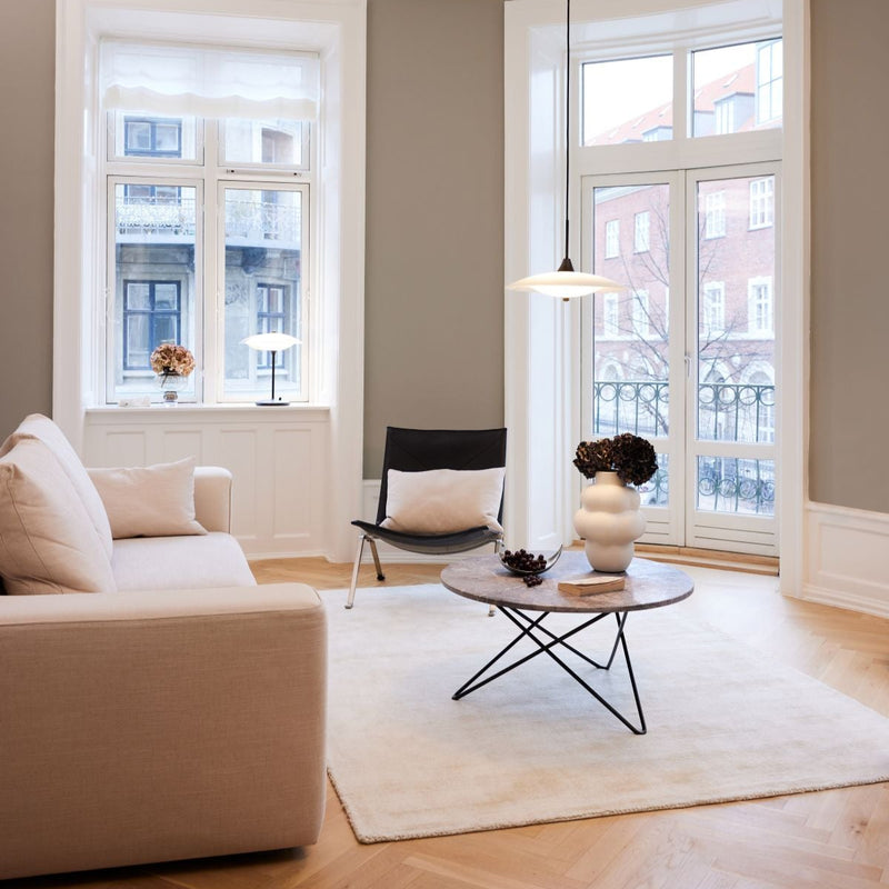 Modern living room with a beige sofa, black chair, and round coffee table.