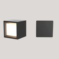 Black square wall light with a glowing interior on a gray background
