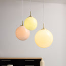 Three spherical  Halo Design Candy Ball pendant lights in pastel colours hanging against a plain background.