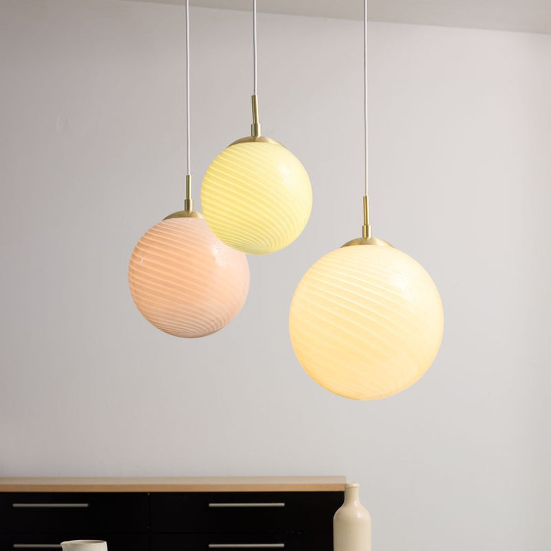 Three spherical  Halo Design Candy Ball pendant lights in pastel colours hanging against a plain background.
