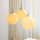Collection of three Halo Design Candy Ball pendant lights hanging against a Light curtain background