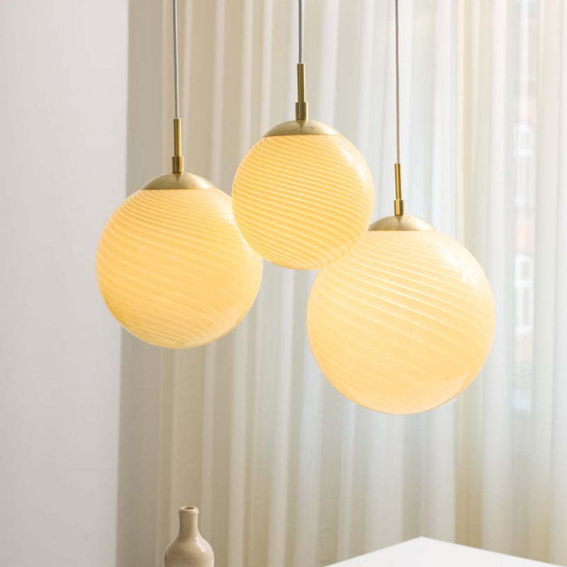 Collection of three Halo Design Candy Ball pendant lights hanging against a Light curtain background