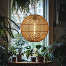 Globe Rattan Lampshade in a room full of houseplants, hung in front of a window