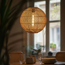 Thatch Globe Woven Rattan Lampshade above a dining table in front of a window