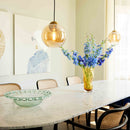 Two Halo Design Bubbles glass pendant lights in amber, 24cm spheres design hanging above a marble dining table