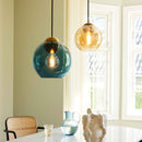 Halo Design Bubbles glass pendant light in blue and amber, 24cm sphere pendants hanging in a dining area