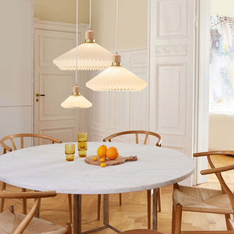 Dining room with a round marble table, wooden chairs, and pendant lights.