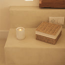 Wicker basket and white candle on a beige surface with a neutral wall background