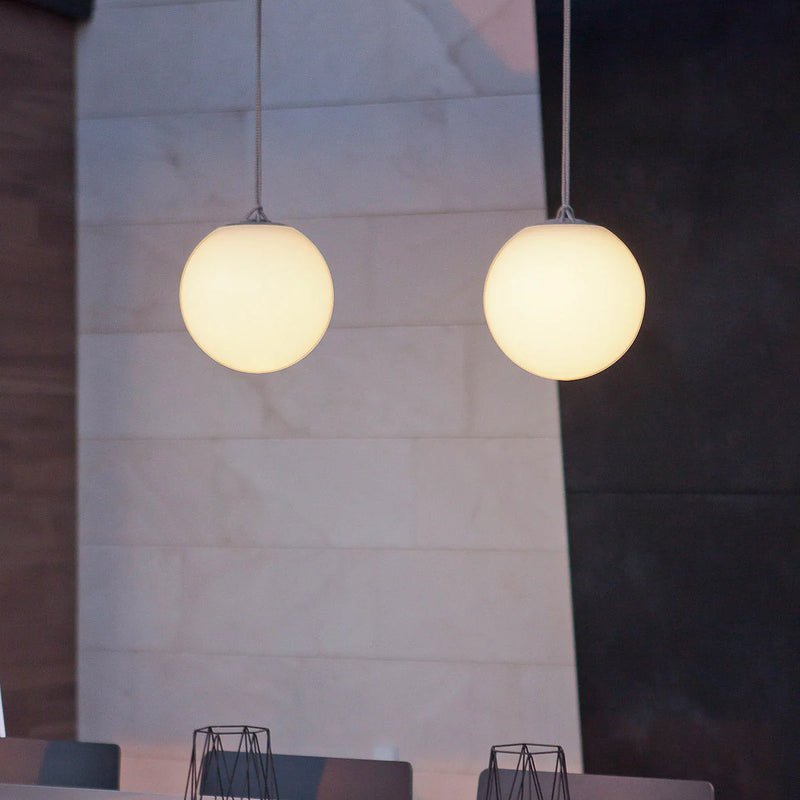 Two round pendant lights hanging from a ceiling with a neutral wall background.