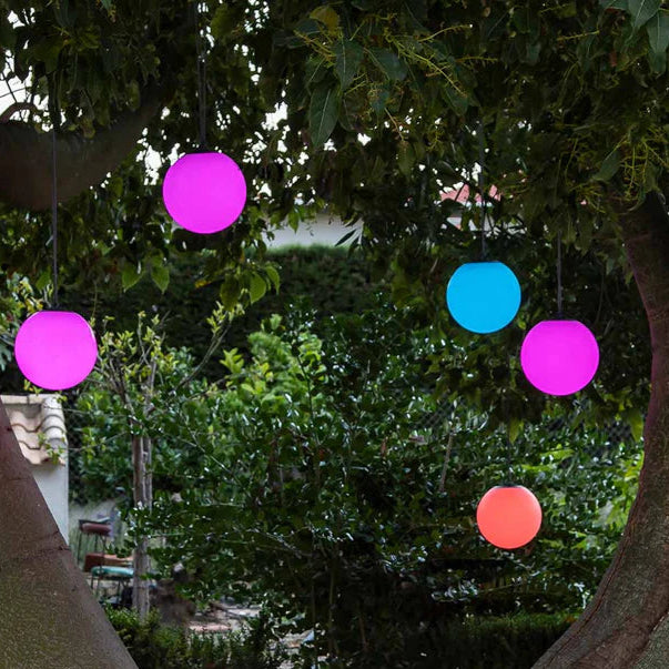 Colorful spherical lights hanging among trees in an outdoor setting