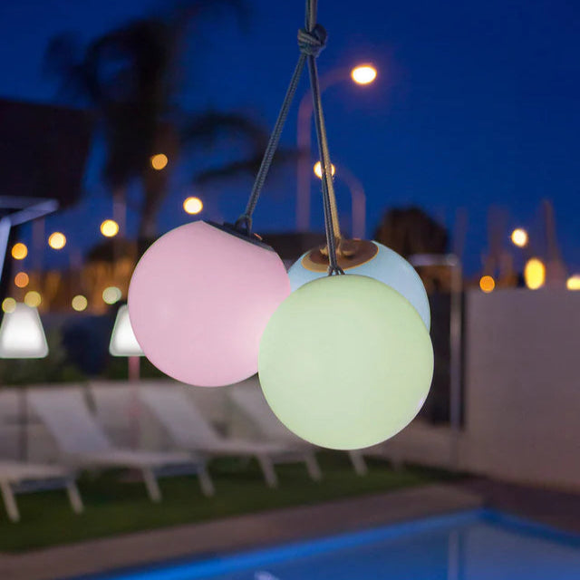 Colorful outdoor string lights hanging over a pool area at night.