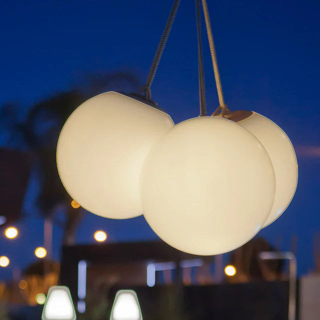 Three illuminated spherical pendant lights hanging against a night sky.
