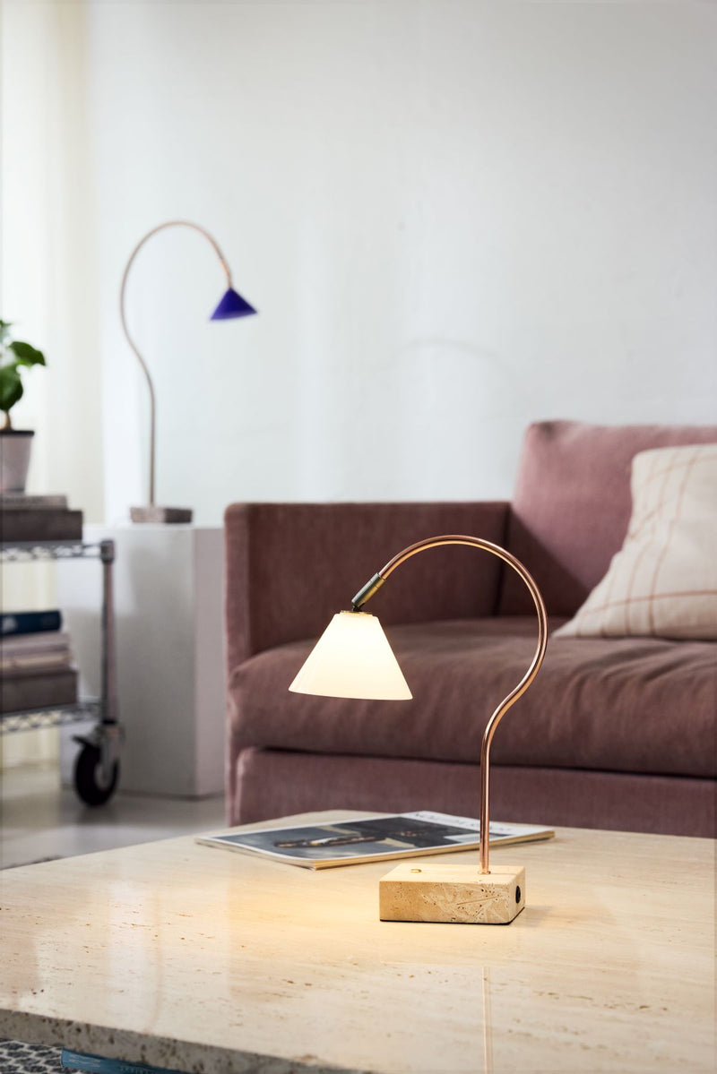 Modern table lamp on a wooden surface with a living room background
