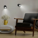 Modern armchair with a yellow vase and glasses on a white surface, illuminated by wall lights.