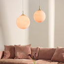 Pink sofa with decorative pillows in a living room setting with 2 Halo Design  Candy Ball pendant lights  in Rose