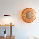Clava Wall Light by Umage casting light patterns on the wall next to shelves with an Umage Asteria Lamp and plant on them