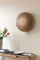 Large Clava Wall Light By Umage above a sideboard with flowers and books.
