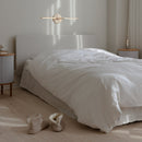 Umage Omni Wall Light horizontally positioned above a bed 