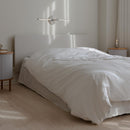 Umage Omni Wall Light in Brushed Steel horizontally above a bed. 