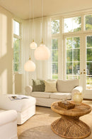 Halo Design Toscana glass pendant lights in opal in three sizes styled in a bright Scandinavian living room with rattan coffee table