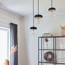 3 clear glass and black Umage Acorn Glass Lampshades hanging i a room next to modern black and glass shelving