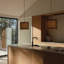  A pair of Umage Komorebi Wooden Lampshades over a kitchen island. Wooden light shades casting a warm glow, great for kitchen lighting