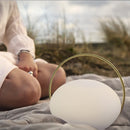 Umage Orbit Portable Table Lamp on a picnic blanket on a beach