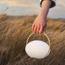 Umage Orbit Portable Table Lamp being carried in the sand dunes on a beach