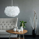 Umage White Feather Lampshade hanging over a relaxing chair and Table adding a soft touch to the room